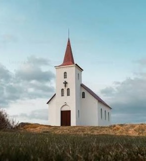 Small white church with a red steeple standing in an open field